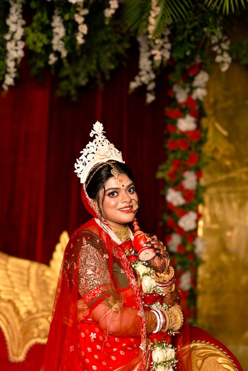 Free A beautiful Indian bride in traditional red attire with intricate jewelry and floral decor. Stock Photo