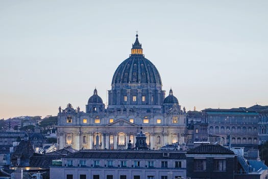 Beautiful dusk view of St. Peter's Basilica with lights glowing in Vatican City.