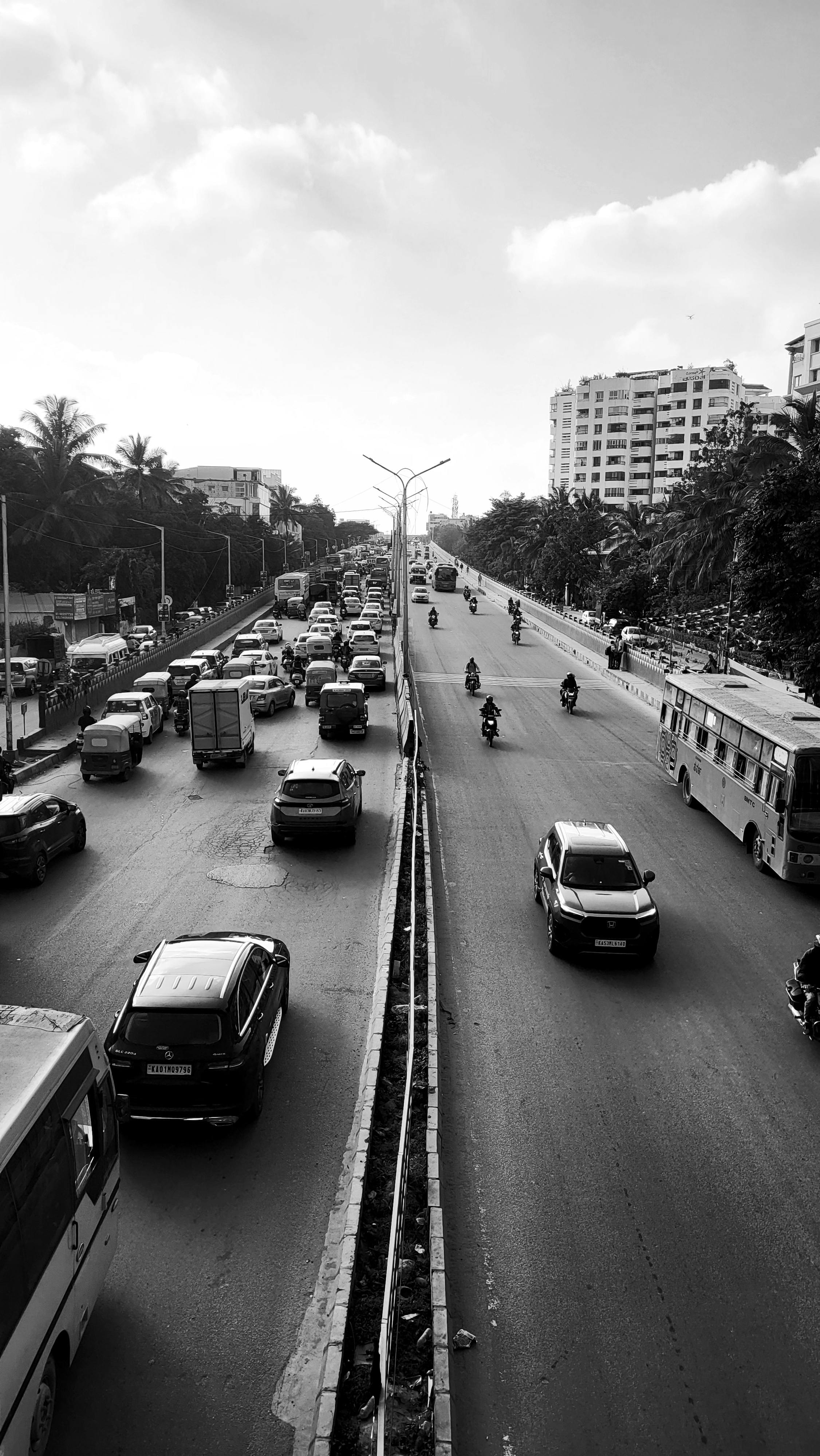 Black and white photo of bustling city traffic on an urban street featuring cars and bikes.