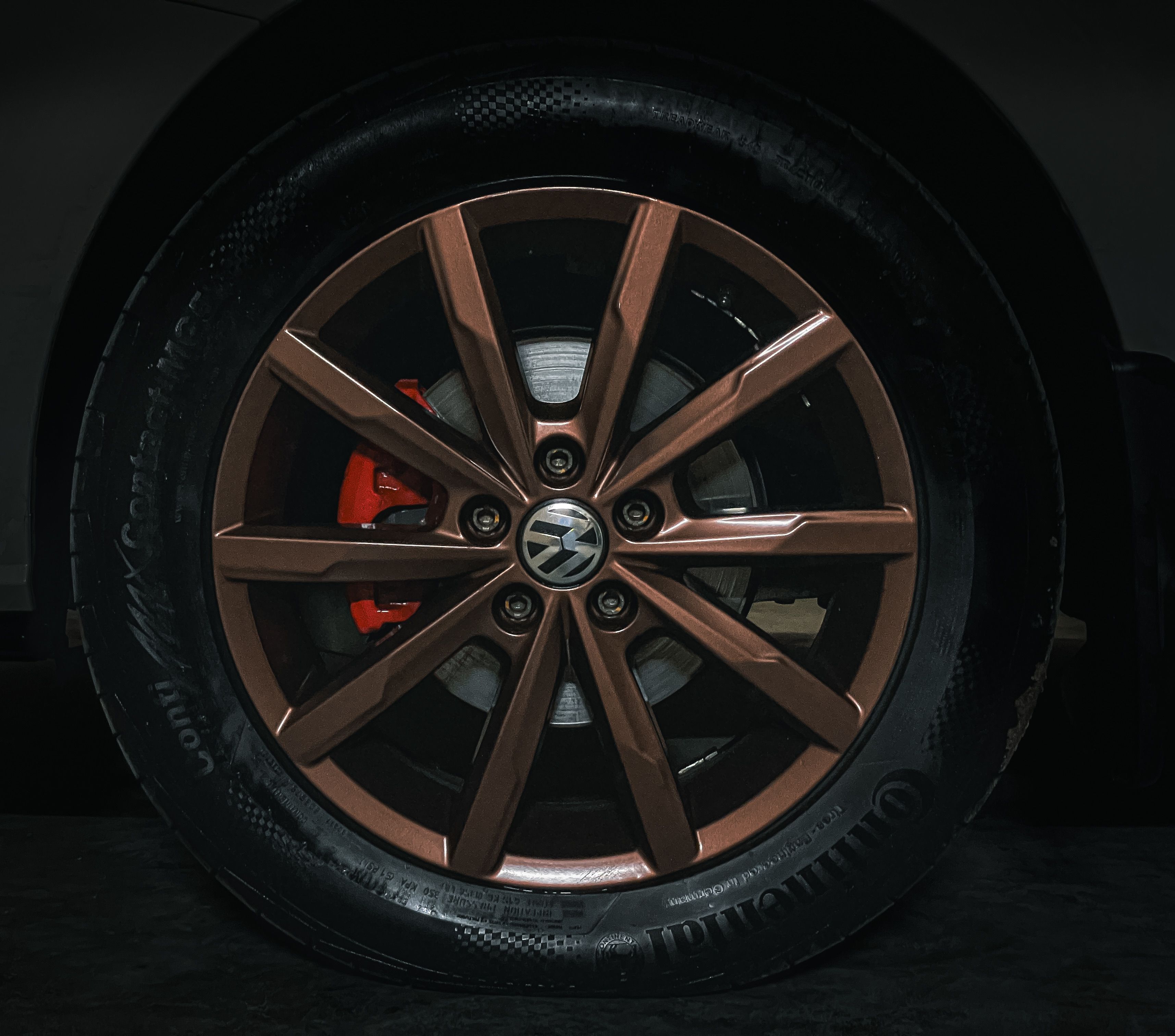 Close-up view of a sleek Volkswagen alloy wheel with a modern design set against a dark backdrop.