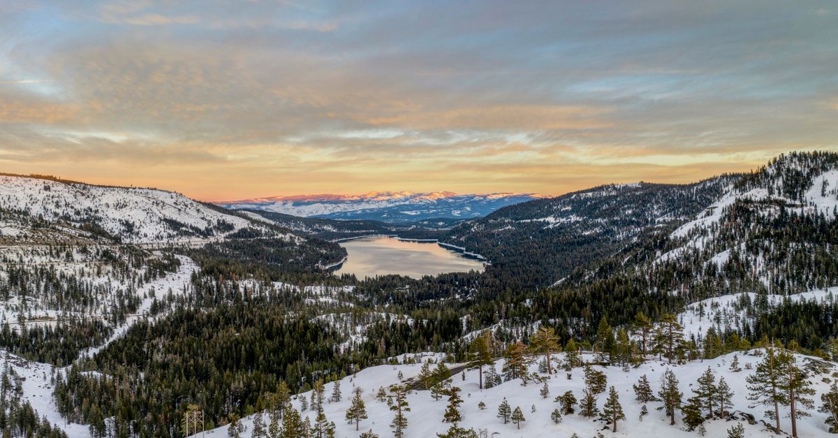 Breathtaking winter view of Donner Lake and surrounding mountains at sunset, ideal for travel and nature themes.