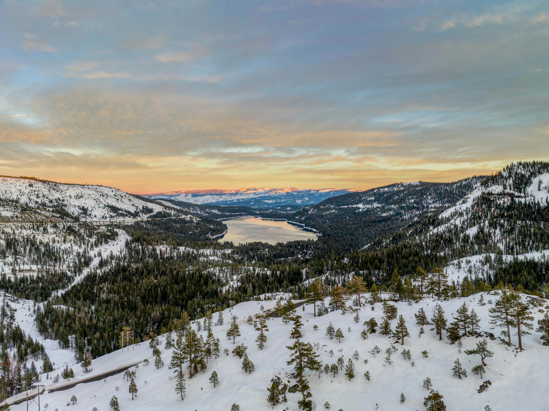 Breathtaking winter view of Donner Lake and surrounding mountains at sunset, ideal for travel and nature themes.