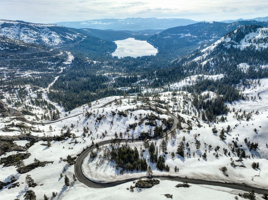Explore the winter landscape of Donner Lake surrounded by snow-covered mountains.