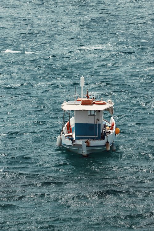 Free A solitary boat gently floats on the shimmering waters of Naxos, Greece. Stock Photo