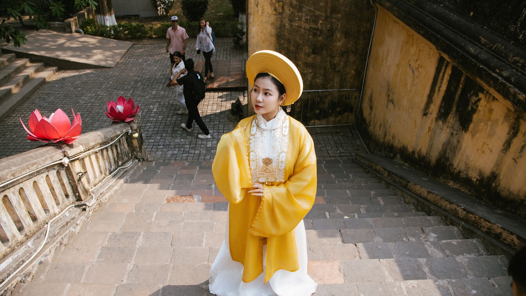 Woman in traditional Vietnamese dress at a historical site in Hà Nội, Vietnam. Captured with natural lighting.