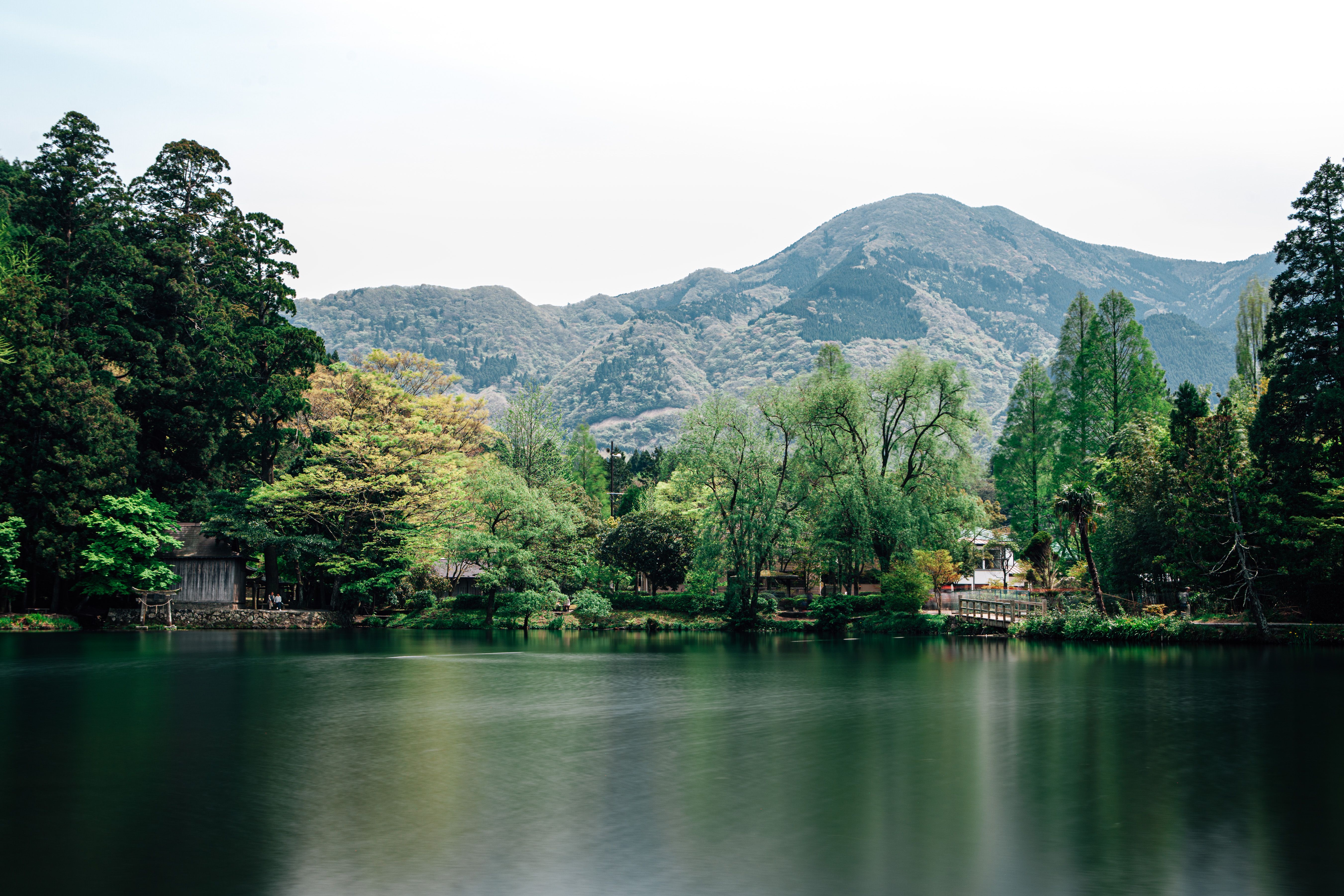 Peaceful mountain lake with lush green foliage and towering mountains in the background.