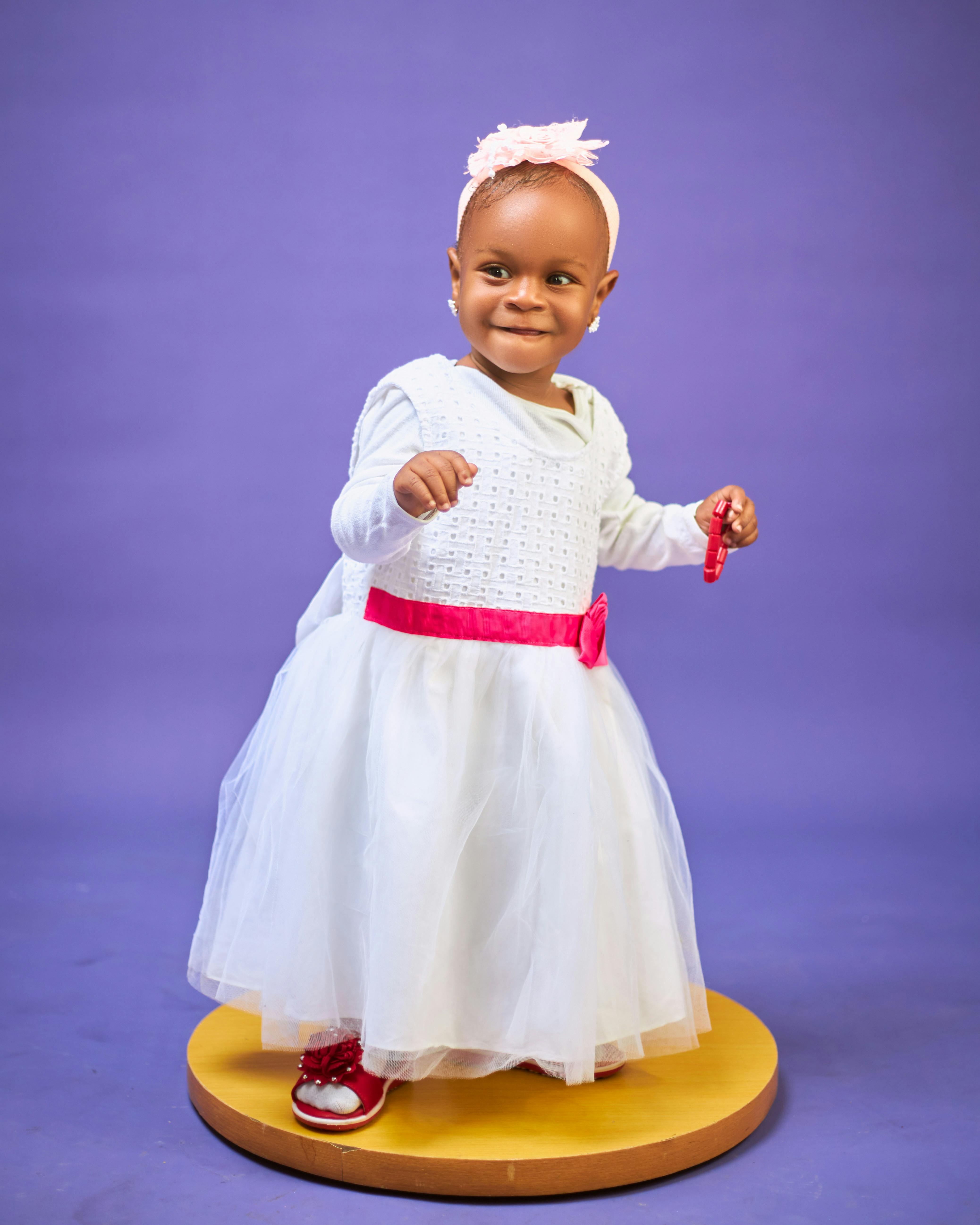 Gratuit Charmant bébé en robe blanche et bandeau rose sur fond violet. Photos