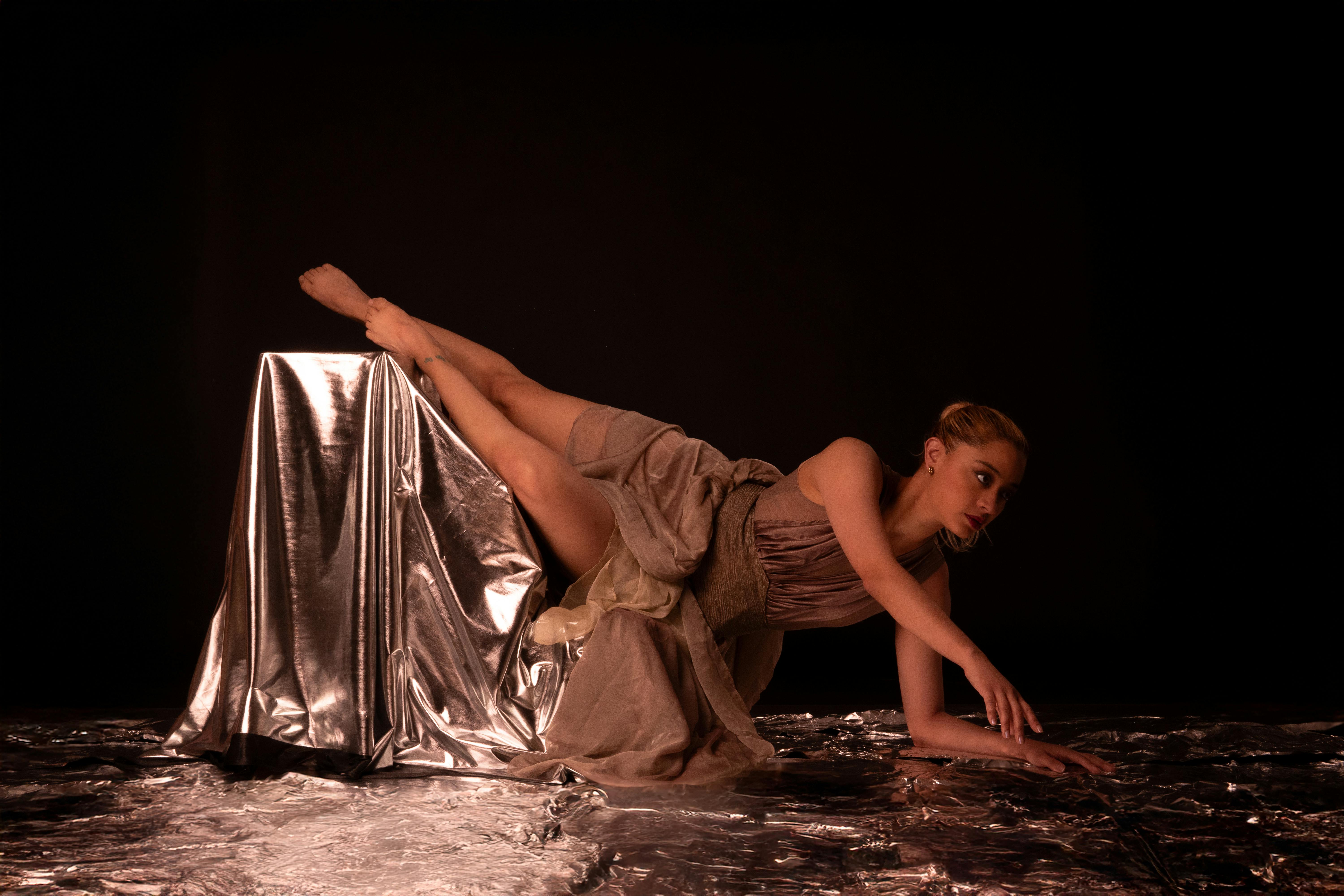 Ücretsiz Dramatik siyah bir fon önünde metalik folyo üzerinde çağdaş bir dansçının sanatsal fotoğrafı. Stok Fotoğraflar