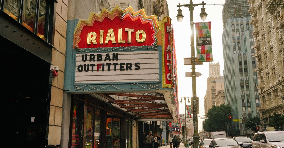 Street view of Rialto Theater sign in Los Angeles Fashion District with people and cars on a busy day.