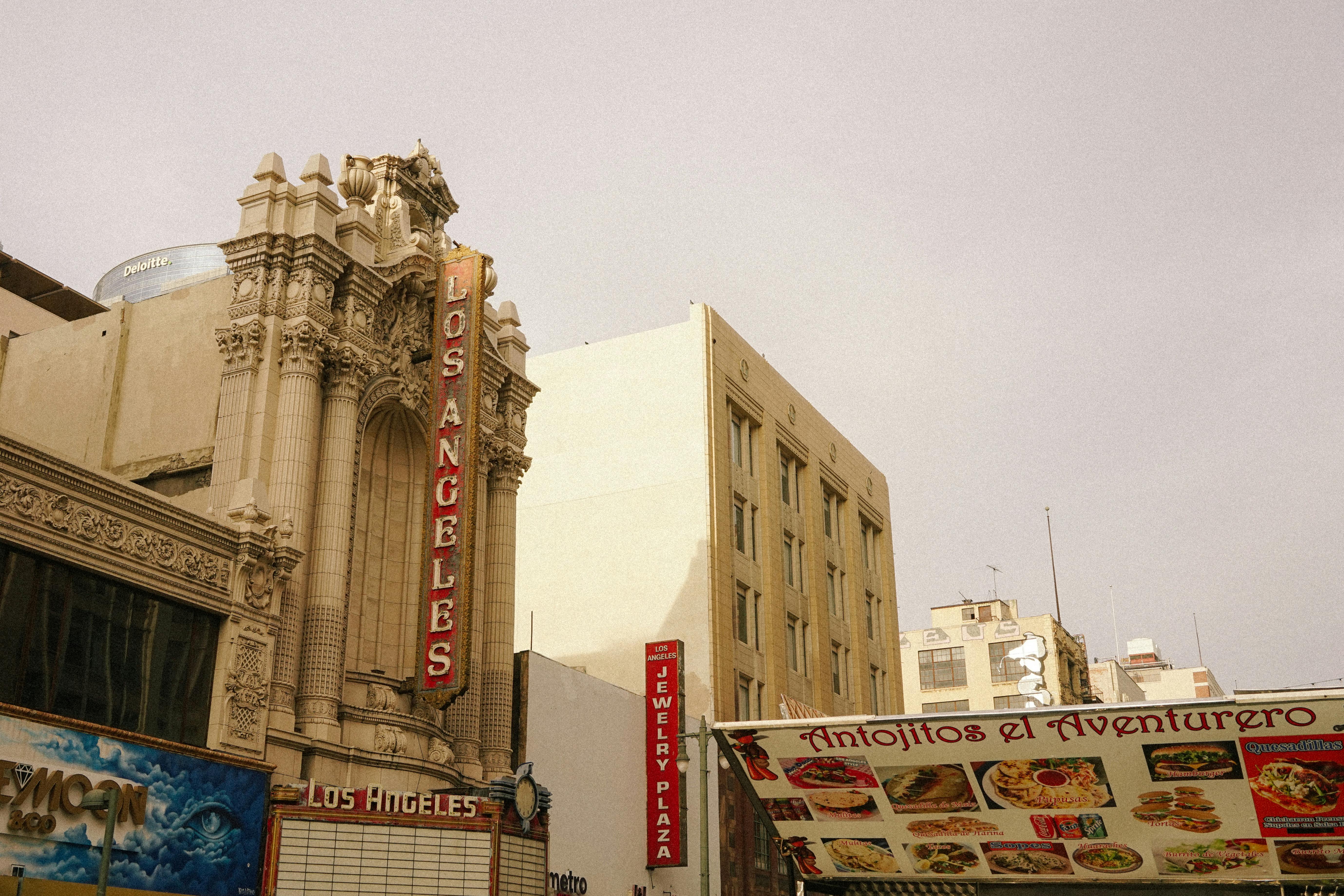 grátis Uma vista vintage de um teatro de Los Angeles com um movimentado mercado de rua em primeiro plano. Foto profissional