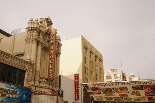 Free A vintage view of Los Angeles theater with a bustling street market in the foreground. Stock Photo