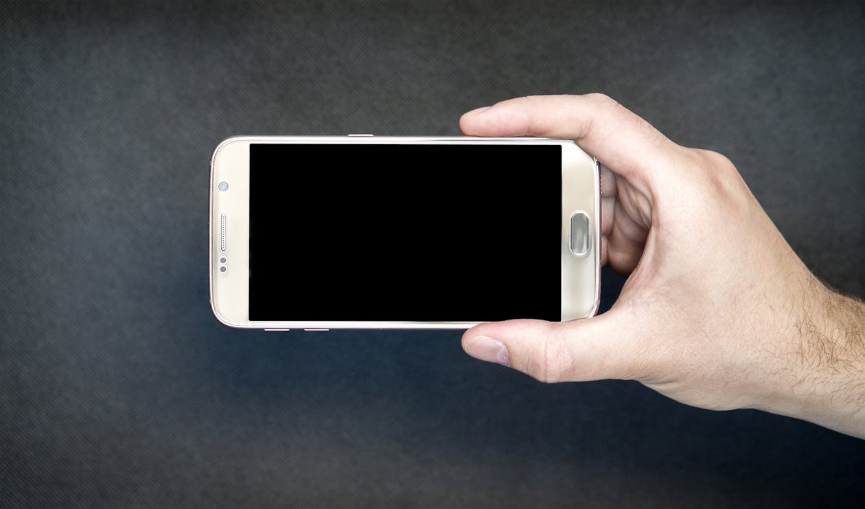 무료 검은 화면으로 Android 스마트 폰을 들고있는 사람 스톡 사진