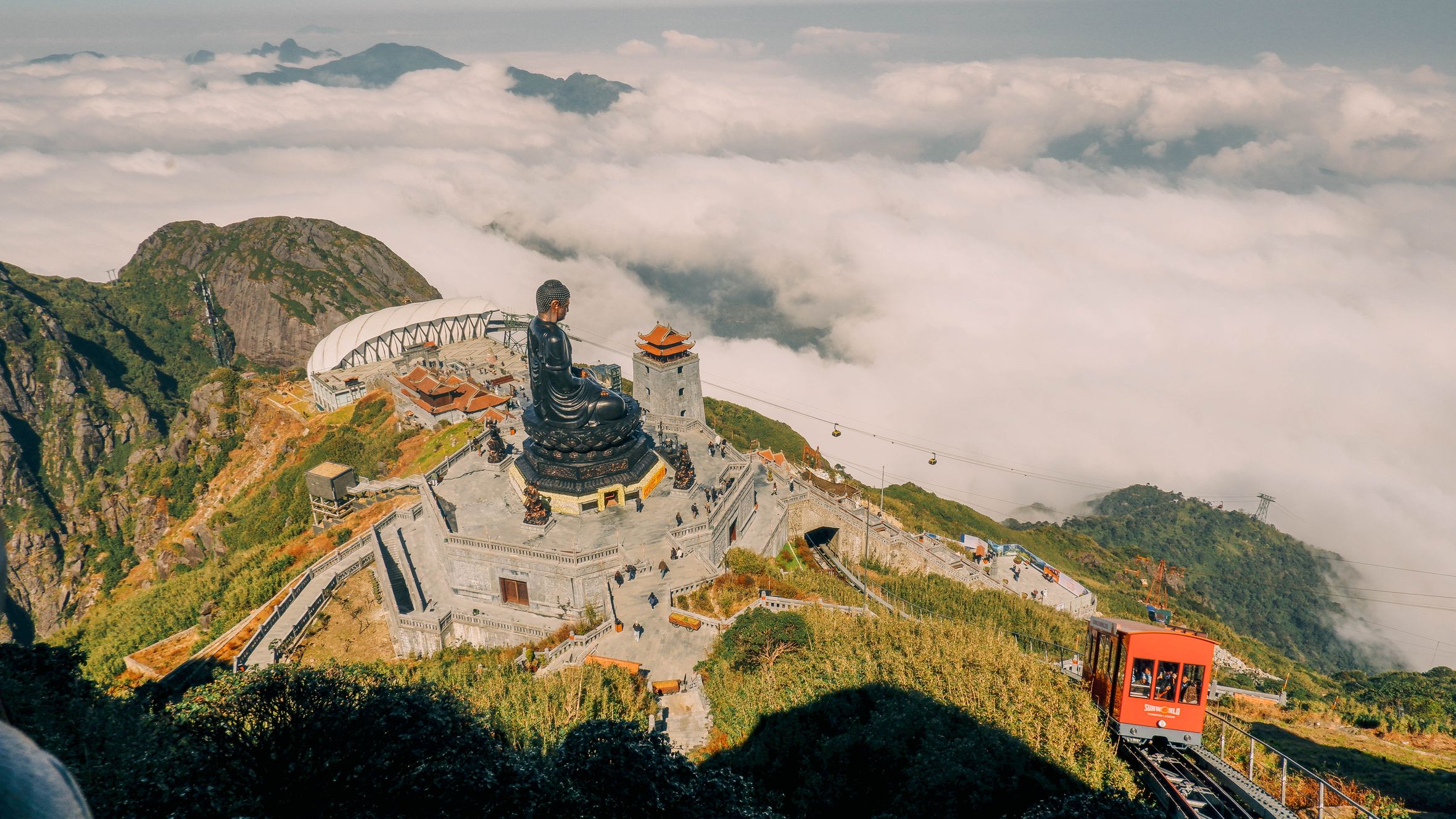 Aerial view of Fansipan Mountain in Lao Cai, Vietnam with a large Buddha statue and scenic cable car ride.