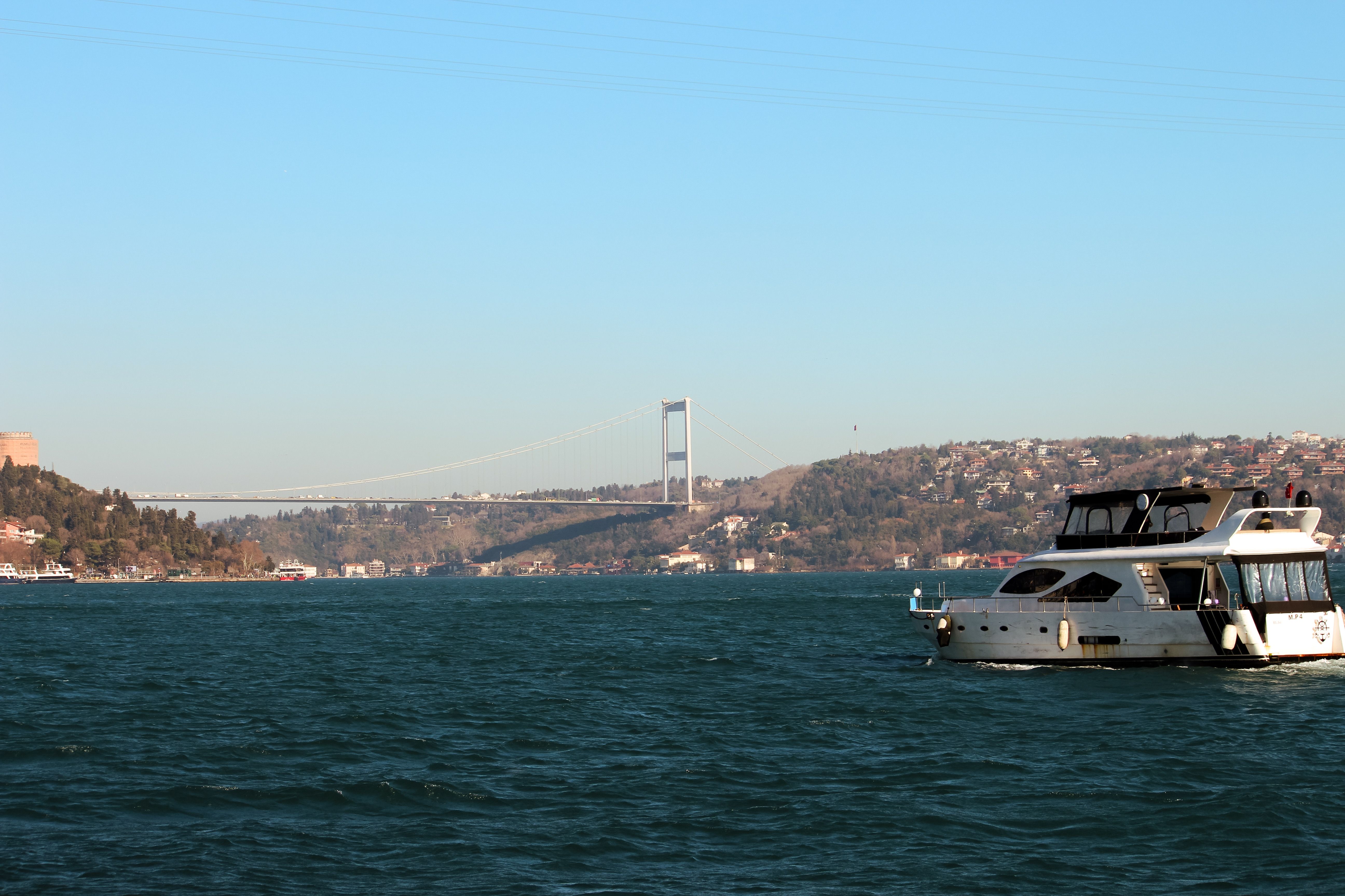 Free Elegant boat navigating the Bosphorus with the iconic Bosphorus Bridge in the background. Stock Photo