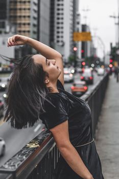 年轻女子在繁华的街道上摆出时尚的姿势，融入城市氛围