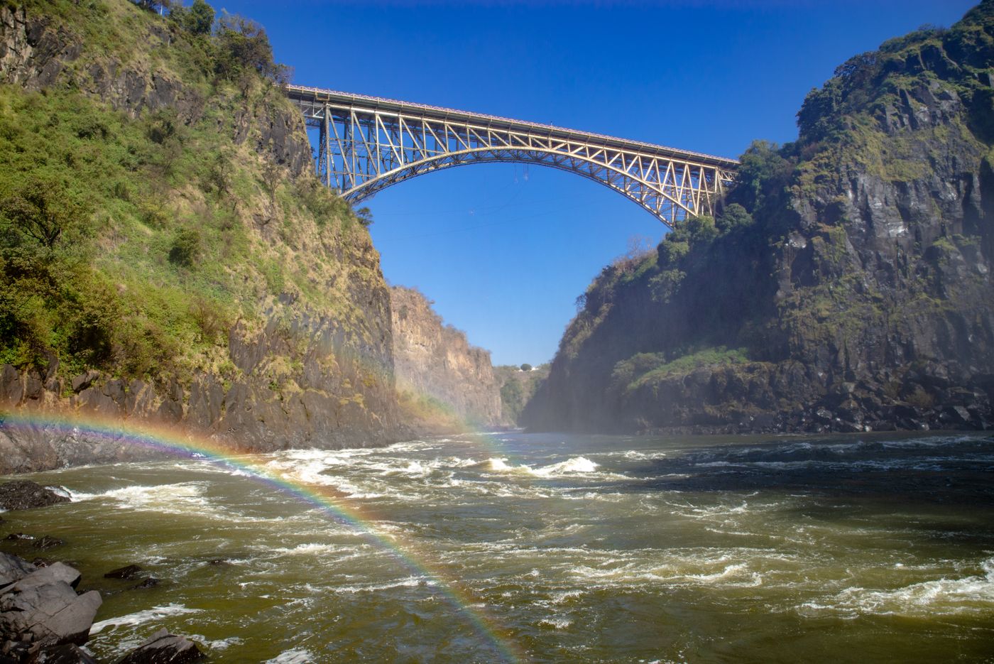 The Victoria Falls Bridge spanning the gorge, with a rainbow in the spray