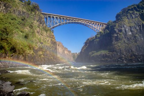Free Stunning view of Victoria Falls Bridge surrounded by cliffs and a vibrant rainbow. Stock Photo