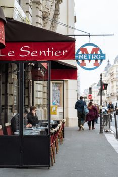 Lively Paris street view with a cafe and Le Sentier Metro sign, showcasing city life.