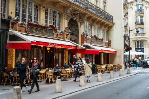 A classic Parisian bistro with outdoor seating and vibrant street life in Paris, France.