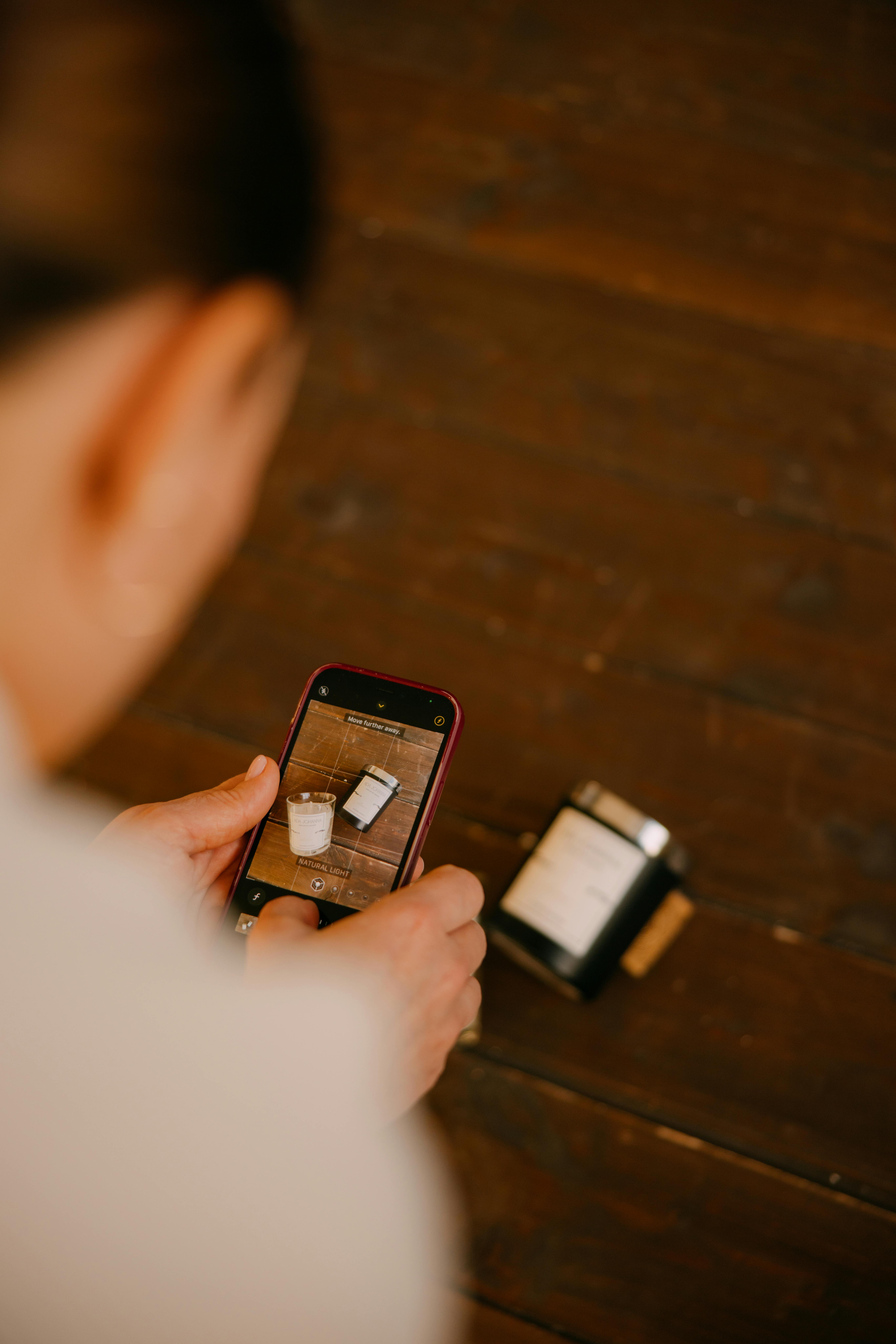 Kostnadsfria En person som fotograferar en minimalistisk kaffe- och ljusinställning på ett träbord. Stock foto