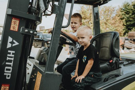 Two young boys explore a stationary vehicle outdoors, embodying play and curiosity.