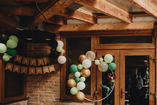 Cozy indoor birthday party scene with green, gold, and white balloon decorations.