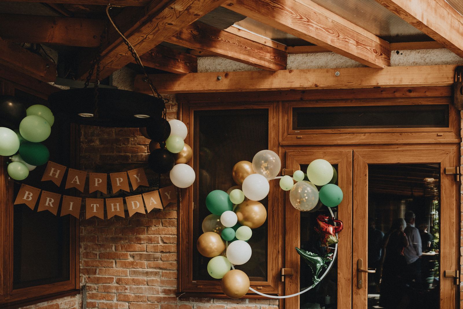 Cozy indoor birthday party with green gold and white balloon decoration