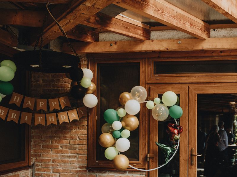 Green, gold and white balloon decorations indoors