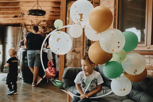A young boy with balloons at an indoor birthday party gathering.