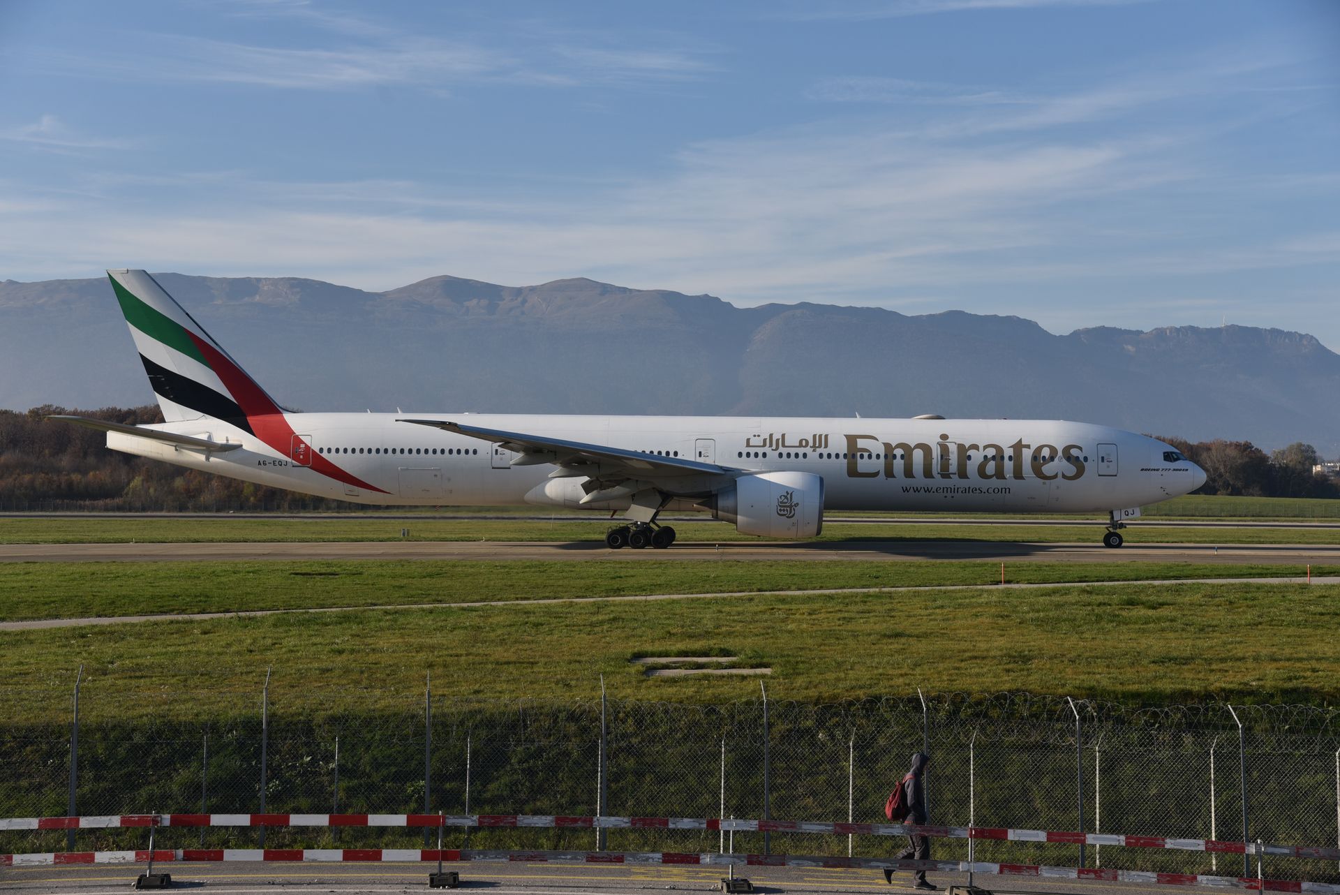 United Arab Emirates Emirates plane taxiing at Genève Airport with mountains in the background.