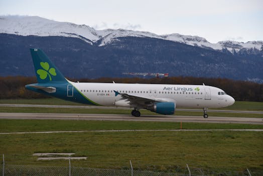 Aer Lingus aircraft taxiing at Geneva Airport with scenic mountain backdrop.