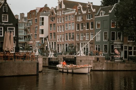 Idyllic view of Amsterdam canal with a boat passing by historic buildings.