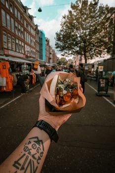 Hand holding a bao bun at an outdoor market in Amsterdam.