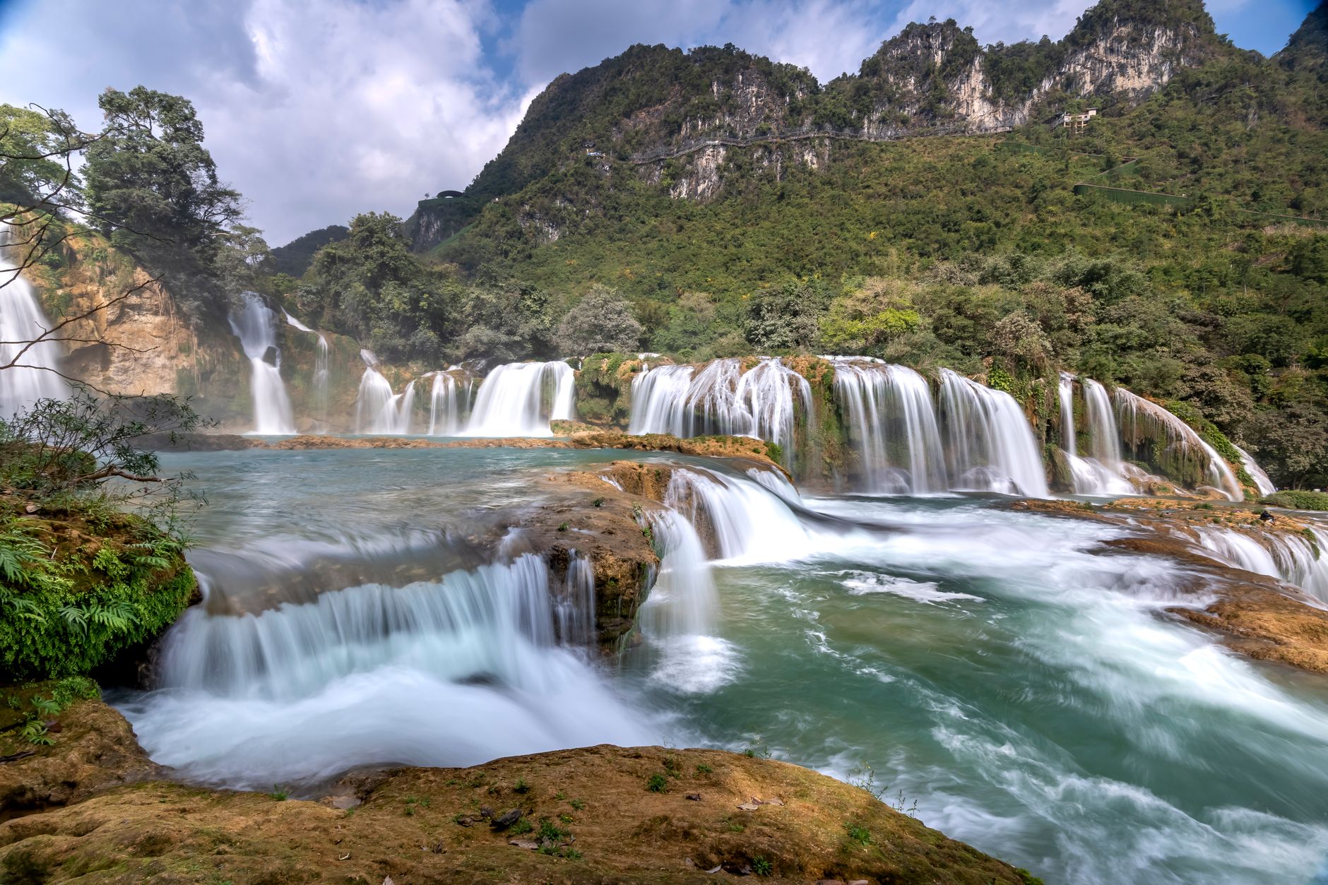 Majestic waterfall cascading in lush forest setting, a serene natural wonder at Ban Gioc.