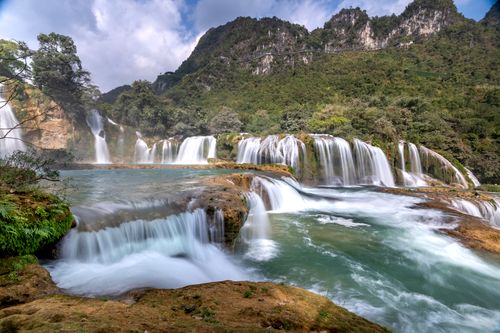Free Majestic waterfall cascading in lush forest setting, a serene natural wonder at Ban Gioc. Stock Photo