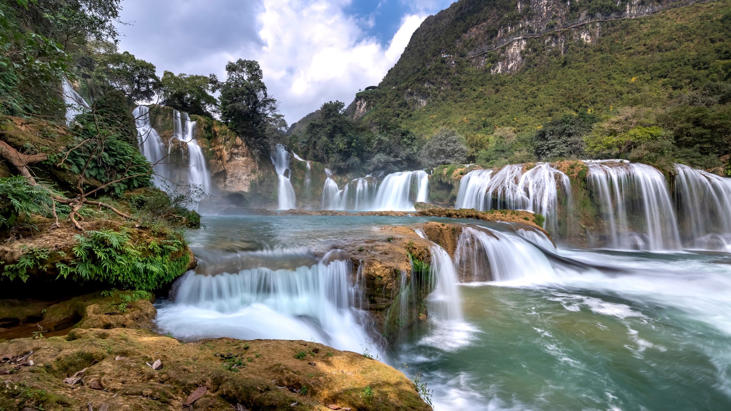 Captivating view of Ban Gioc Waterfalls with lush greenery and clear blue sky.