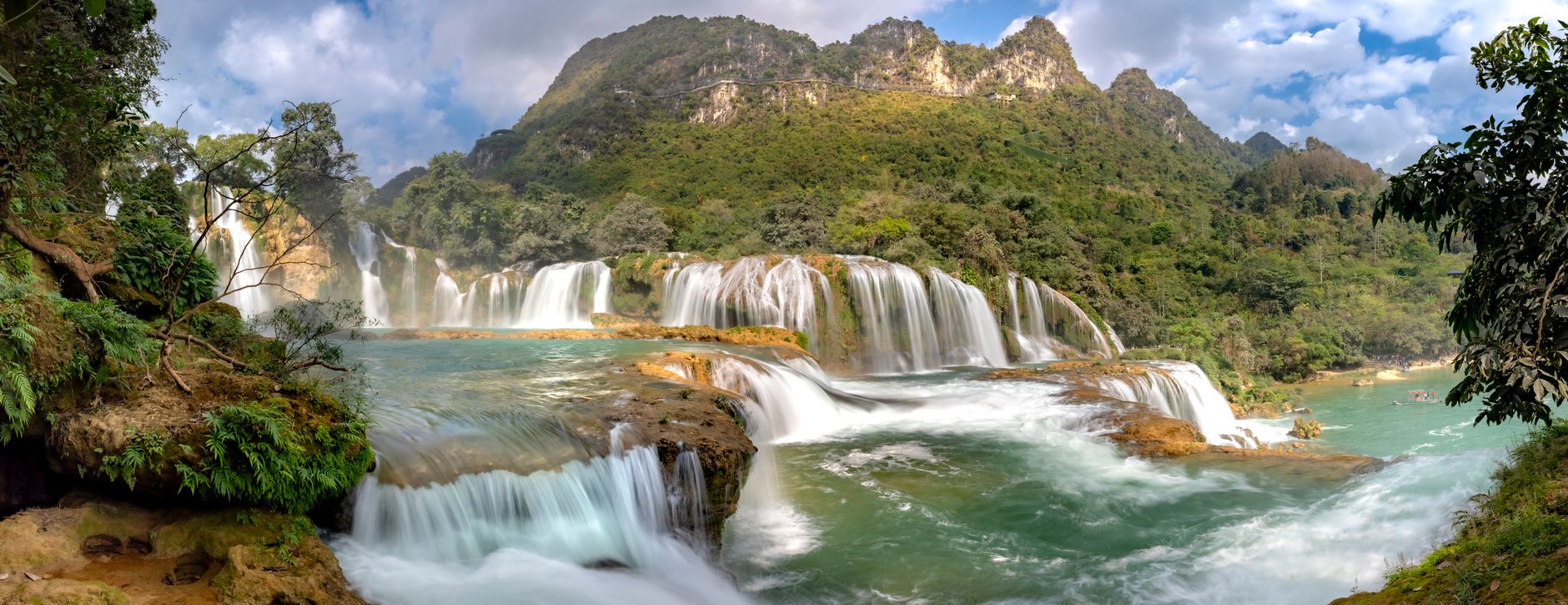 Panoramic view of Ban Gioc Waterfall, lush greenery and cascading streams.