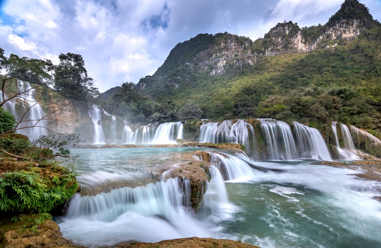 stunning view of cascading waterfalls amid lush mountains under a blue