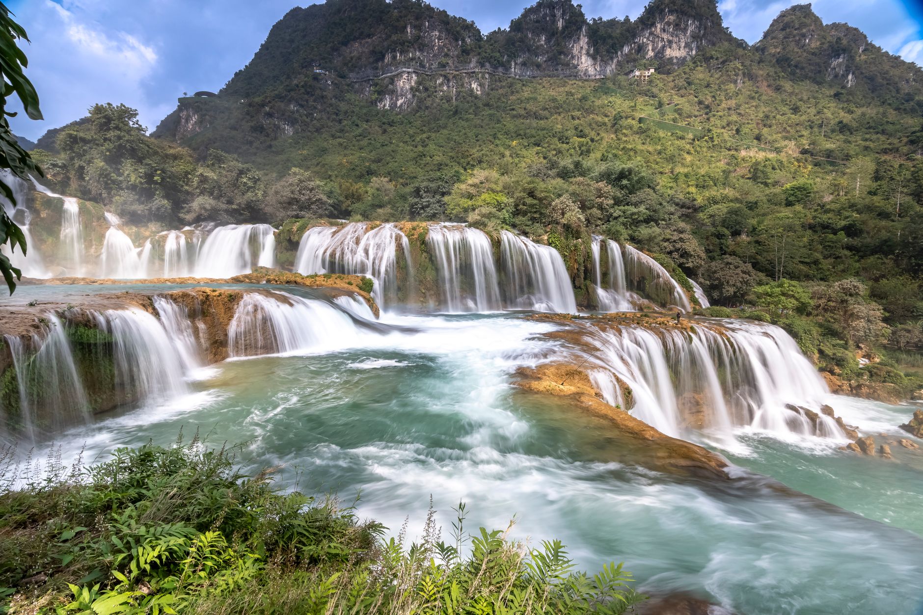 Breathtaking view of a cascading waterfall surrounded by lush greenery and mountains.