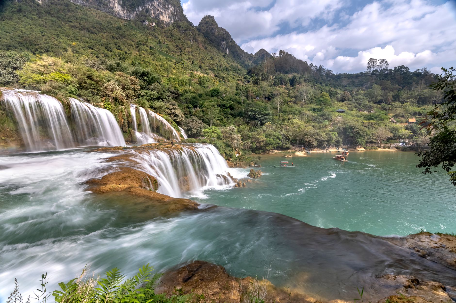 Stunning view of Ban Gioc Waterfall surrounded by lush greenery and mountains in Vietnam.