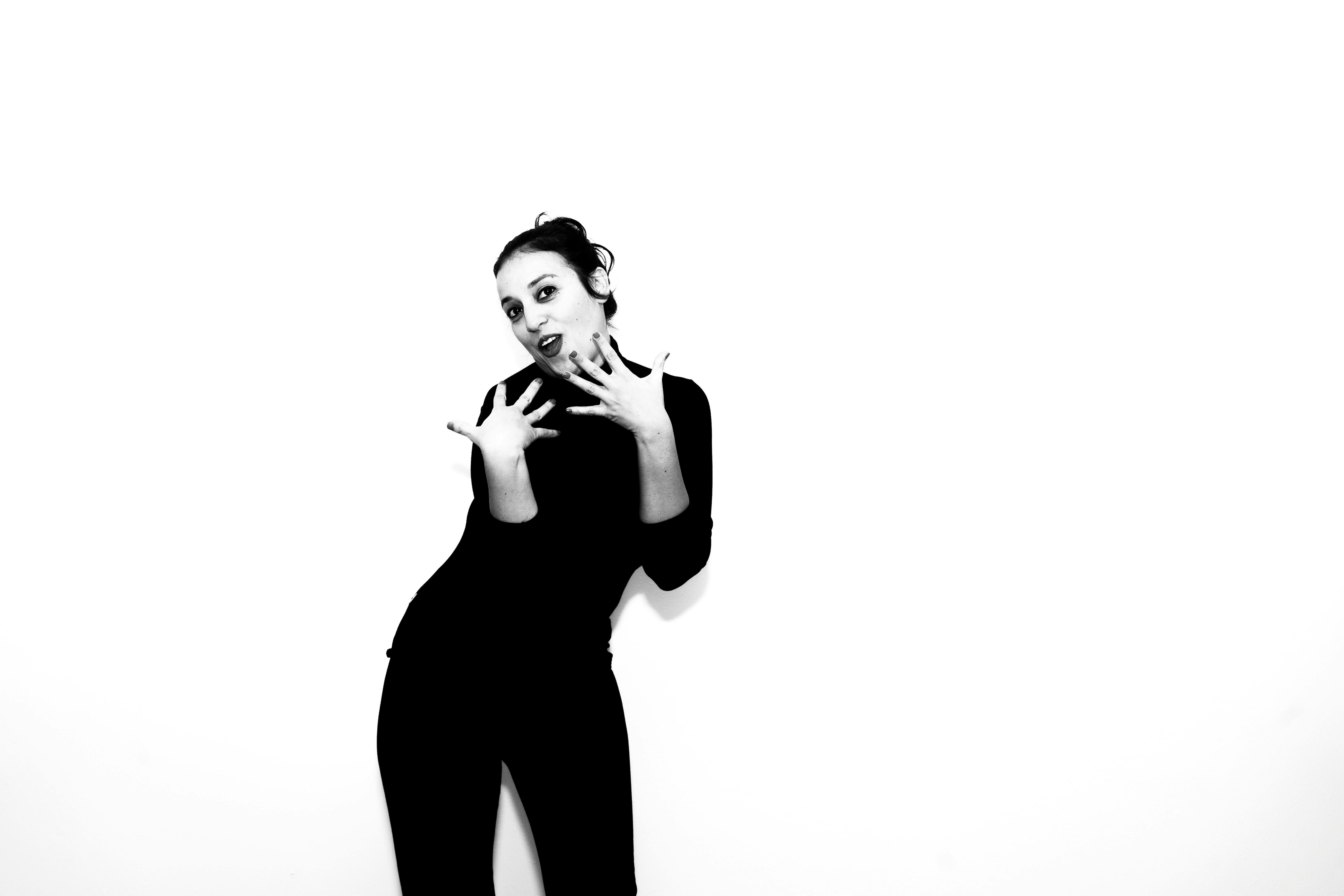 Gratuit Portretul alb-negru al unei femei care gesticulează jucăuș pe un fundal alb. Expresie captivantă. Fotografie de stoc