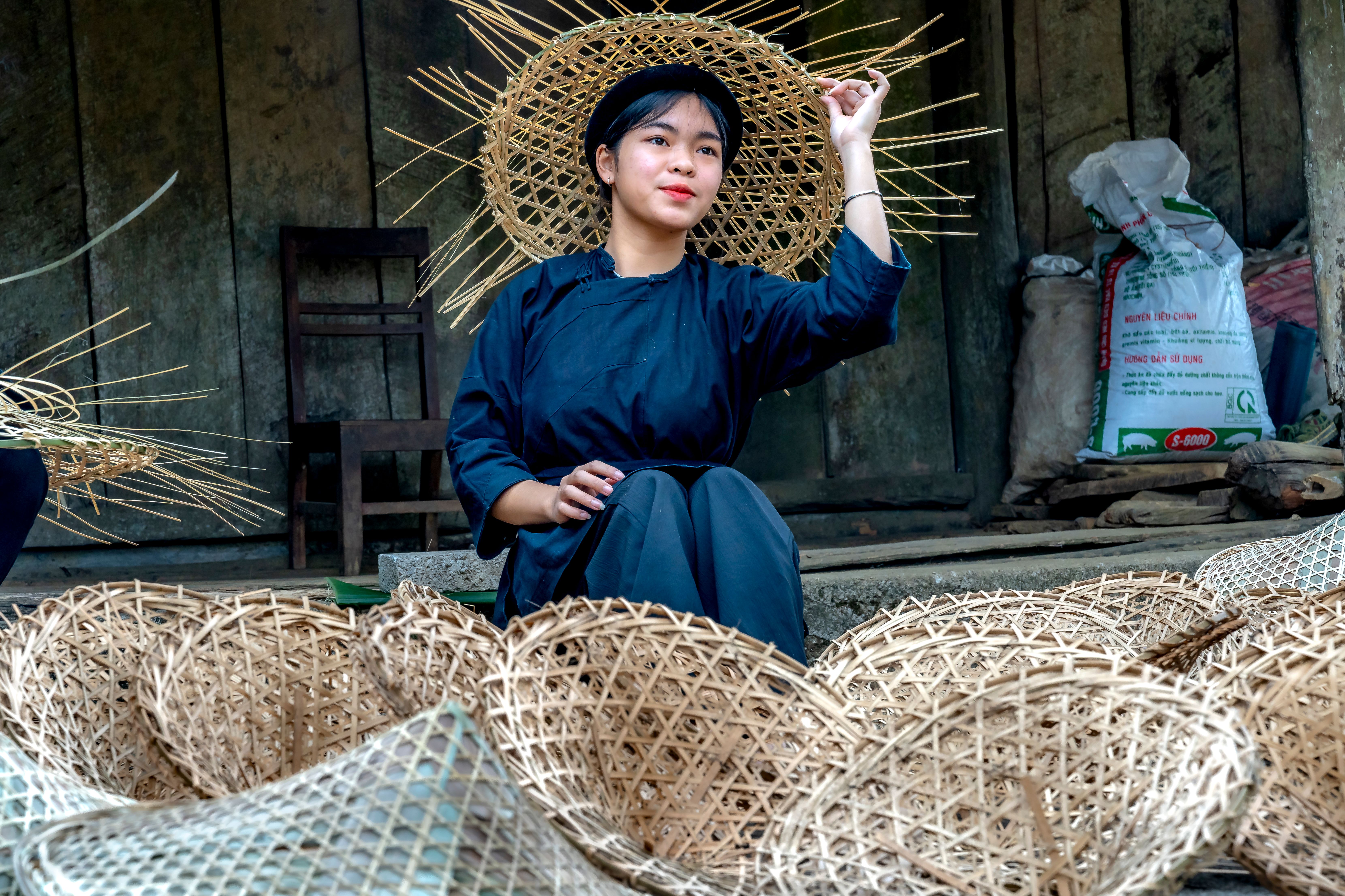 A woman in traditional attire crafting bamboo baskets, showcasing Vietnamese culture.