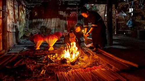 Free A scene depicting traditional incense making indoors with two people tending a fire. Stock Photo