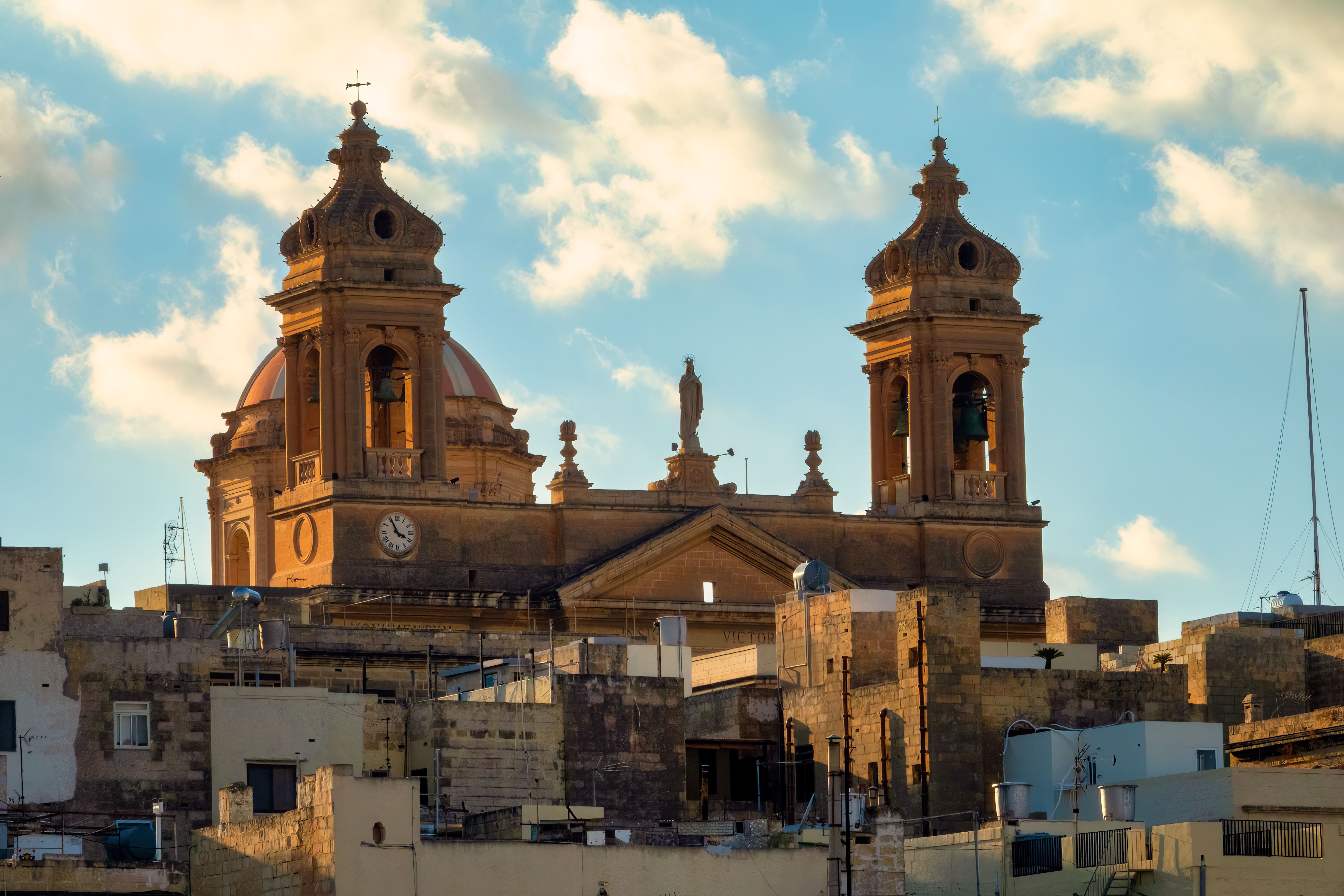 Majestic view of a historic church with twin towers in Malta under a bright blue sky.