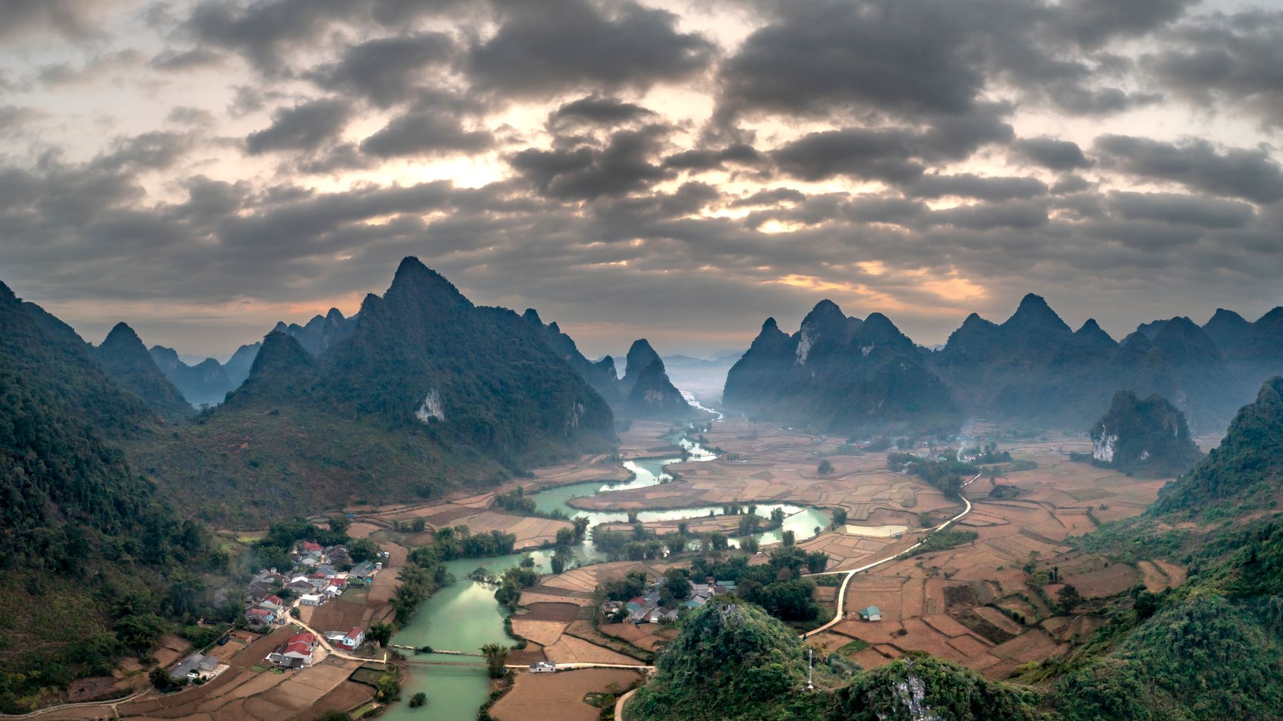 Aerial view of karst mountains with villages and river in a rural landscape.