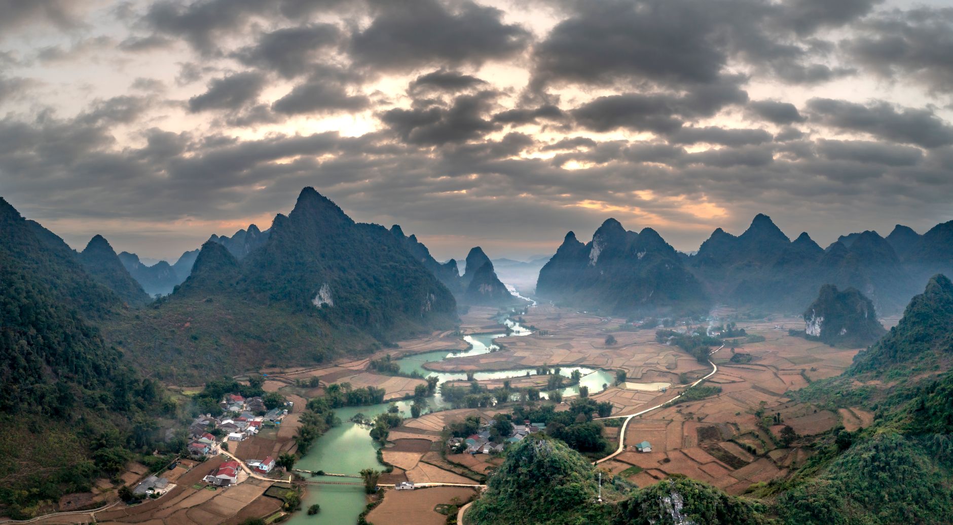 Aerial view of karst mountains with villages and river in a rural landscape.