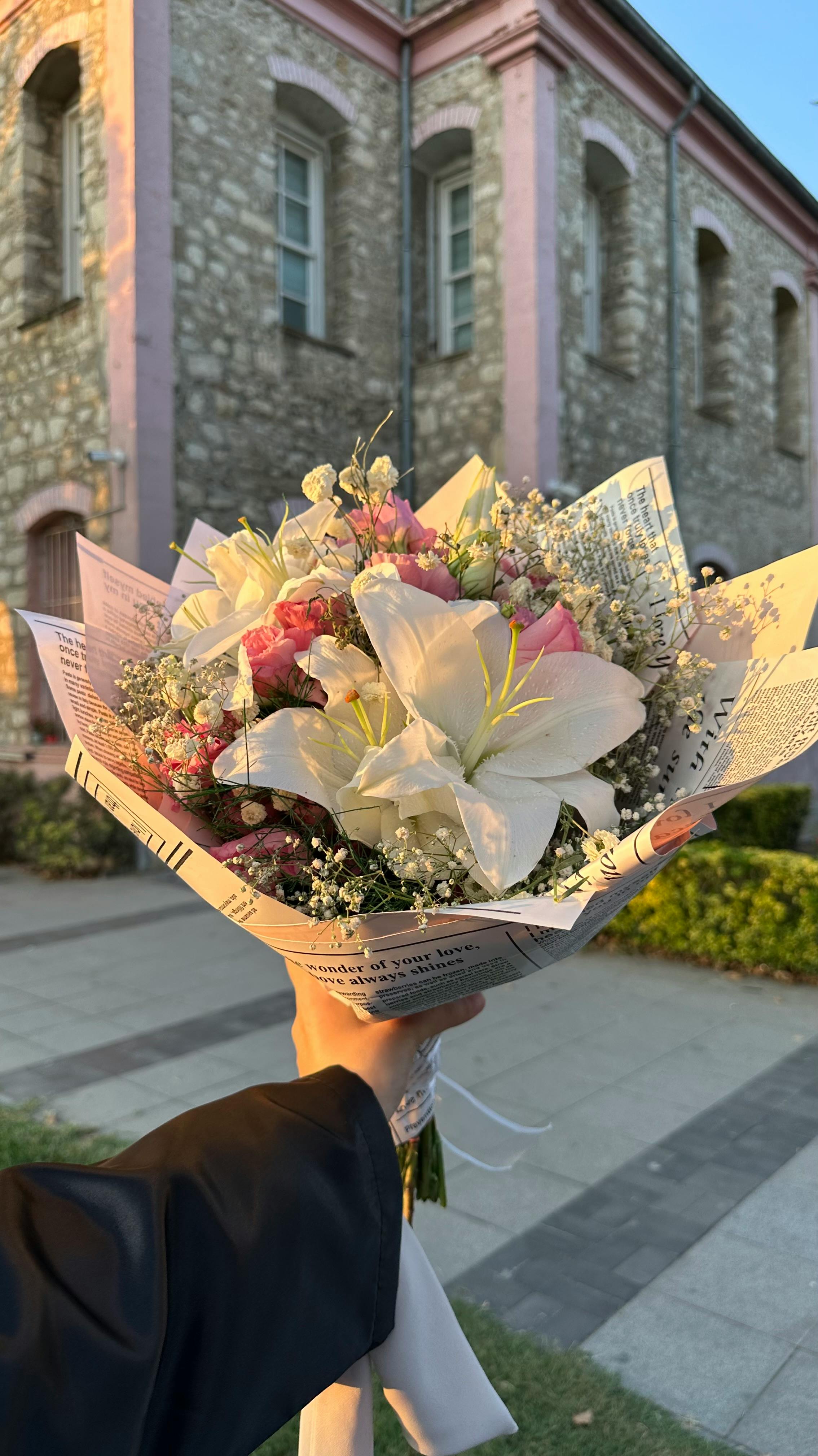 A beautifully crafted bouquet with white lilies held against a historic building background.