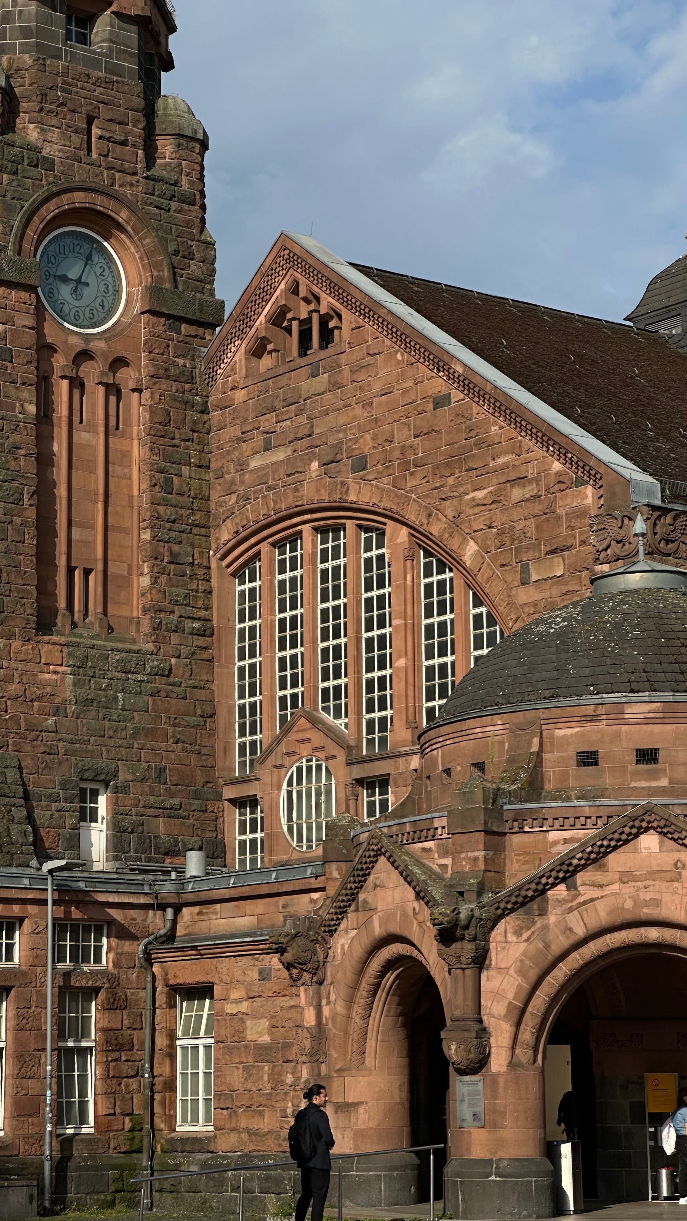 A stunning red brick architecture and clock tower under a blue sky.