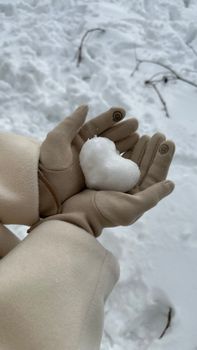 Heart-shaped snowball in gloved hands, capturing the essence of a serene winter day.