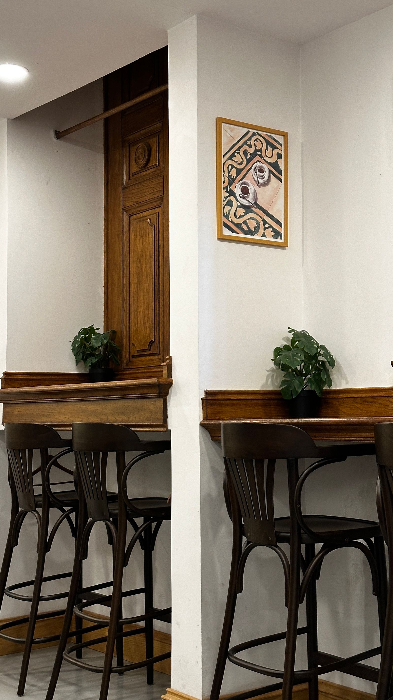 Cafe stools beside warm wood panelling and plants.